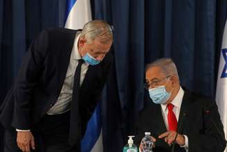 FILE PHOTO: Israeli Prime Minister Benjamin Netanyahu speaks with Alternate Prime Minister and Defence Minister Benny Gantz, as they both wear a protective mask due to the ongoing coronavirus disease (COVID-19) pandemic, during the weekly cabinet meeting in Jerusalem June 7, 2020. Menahem Kahana/Pool via REUTERS/File Photo