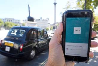 Táxi em Londres passa enquanto aplicativo do Uber é mostrado em smartphone em primeiro plano. 22/9/2017. REUTERS/Toby Melville