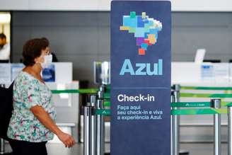 Passageira usando máscara de proteção passa pela frente de guichê da companhia aérea Azul. 11/3/2020. REUTERS/Adriano Machado