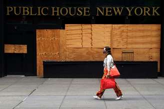 Mulher passa por bar fechado em Nova York. REUTERS/Carlo Allegri