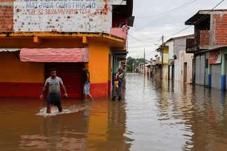 Pessoas caminham por ruas alagadas em Itajuipe, na Bahia - 27/12/2021