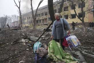 Uma mulher caminha do lado de fora de uma maternidade atingida por um bombardeio russo em Mariupol, Ucrânia