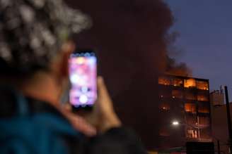 Homem tira foto de incêndio de grandes proporções em prédio comercial na região central de São Paulo