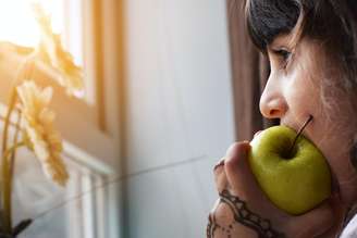 Imagem meramente ilustrativa de uma menina comendo uma fruta