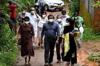 Integrantes de uma equipe médica da Faculdade de Medicina de Kozhikode carregam amostras de noz de areca e goiaba para realizar testes para o vírus Nipah na Vila de Maruthonkara, no distrito de Kozhikode, em Kerala, na Índia.