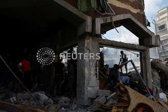 Palestinos caminham em escombros após ataques israelenses em Khan Younis, no sul da Faixa de Gaza
10/10/2023 REUTERS/Ibraheem Abu Mustafa
