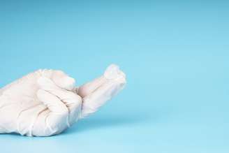 Imagem meramente ilustrativa mostra mão coberta por luvas e gel nos dedos