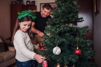 Pai e filha montam árvore de Natal; momento da montagem costuma ser uma tradição familiar