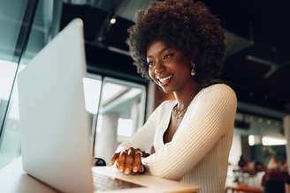 Mulher sorridente realizando inscrição em um concurso público. 