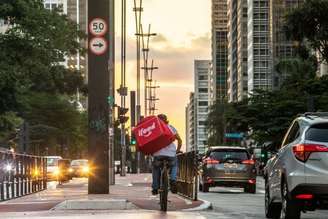 Entregador do aplicativo iFood atravessa a Avenida Paulista, em São Paulo.