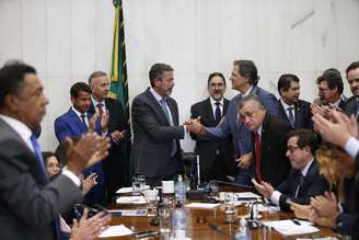 O ministro da Fazenda, Fernando Haddad (D), entre ao presidente da Câmara, Arthur Lira (E), o primeiro projeto de lei complementar que vai regulamentar a reforma tributária promulgada no ano passado pelo Congresso