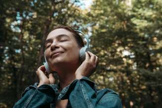 Mulher com fone de ouvido em região arborizada