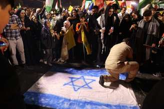 Iraniano pisa em bandeira de Israel durante comemoração em Teerã pelos ataques com mísseis nesta terça-feira (01/10)