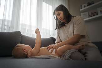 Mãe trocando a fralda do seu bebê.