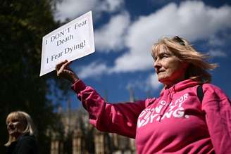 Uma ativista com deficiência da Dignity in Dying segura um cartaz durante protesto em apoio às propostas para legalizar a morte assistida no Reino Unido