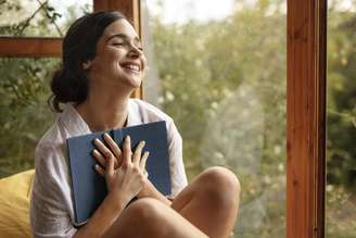 Mulher feliz com seu livro nas mãos.