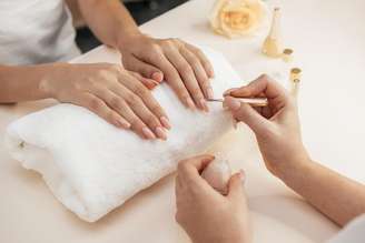 Mulher com manicure pintando as unhas.