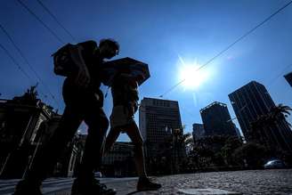 Pedestres caminham pelo Viaduto do Chá em dia de forte calor na cidade de SP.