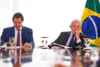 O presidente Luiz Inácio Lula da Silva (PT), e o ministro da Fazenda, Fernando Haddad, juntos, em uma mesa de reunião no Palácio do Planalto. 