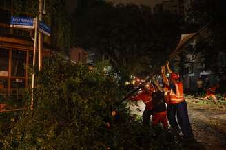 Funcionários da prefeitura de São Paulo levantam poste de sinalização derrubado por árvore em Pinheiros, na zona oeste da capital, durante o temporal desta quarta-feira.