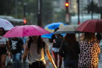 Pedestres caminham com guarda-chuvas na Av. Paulista, em São Paulo, em dia de chuva e queda de temperatura.