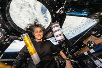Suni Williams posa com amostras de bactérias e leveduras. Ela estudou os efeitos da microgravidade na biofabricação de bactérias e leveduras a bordo da Estação Espacial Internacional.