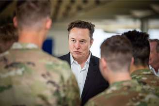 Na imagem Elon Musk, conversando com militares que estão de costas.