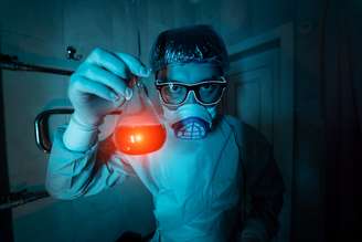 Imagem ilustra uma pessoa, com todo o equipamento de segurança, segurando um vidro com veneno.