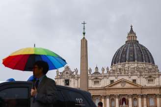 Imagem ilustrativa de homem com guarda-chuva com as cores do arco-íris em frente ao Vaticano