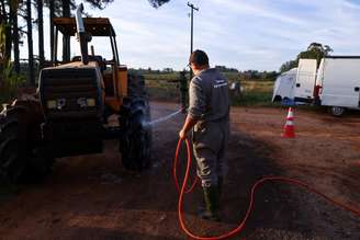 Homem limpa trator numa barreira sanitária em Montenegro (RS)