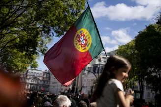 Garota segura bandeira de Portugal em dia ensolarado