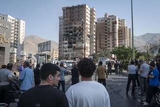 Povo iraniano se reúne no local de uma explosão em um complexo residencial devido aos ataques israelenses em Teerã, Irã, em 13 de junho de 2025.