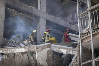 Bombeiros iranianos trabalham no local de um prédio residencial destruído devido aos ataques israelenses em Teerã, Irã, em 13 de junho de 2025.