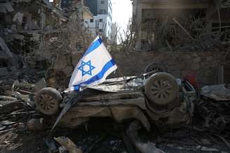 Uma bandeira israelense colocada em um carro danificado pela explosão de um míssil balístico do Irã