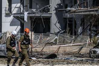 Policiais israelenses e especialistas em desarmamento de bombas são vistos trabalhando no local do impacto após um míssil supostamente lançado do Irã atingir a cidade de Bersheba, no sul de Israel, em 20 de junho de 2025. As autoridades iniciaram investigações após o incidente como parte de medidas de segurança mais amplas em meio às tensões regionais em curso.