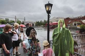 Pessoas passam por um cartaz com a imagem de Putin em um dia chuvoso em Moscou