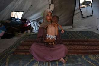 Mãe palestina com seu filho de 18 meses em campo de refugiados em Gaza
