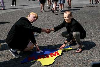 Protesto em Berlim com máscaras de Trump e Putin com a bandeira da Ucrânia