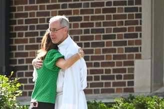 Mulher abraça o clérigo da Escola da Anunciação em Minnesota após tiroteio que matou duas crianças