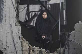 Mulher em meio a destroços de prédio bombardeado por Israel em campo de refugiados