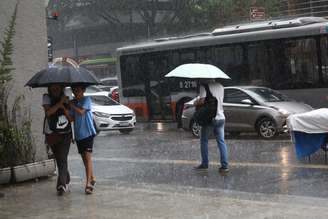 Pedestres se protegem da chuva que cai pela Avenida Paulista, região centro-sul de São Paulo, neste sábado (13).