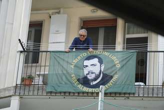 Pai de Alberto Trentini em uma varanda que traz uma faixa pedindo a libertação do filho