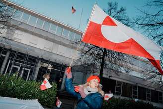 Manifestante com bandeira da Groenlândia em protesto diante da embaixada dos EUA na Dinamarca
