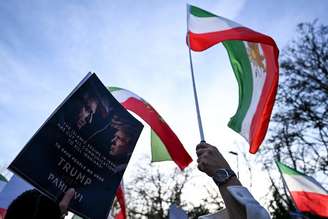 Mulher segurando um cartaz com retratos do filho do último xá do Irã e do presidente dos EUA, Trump