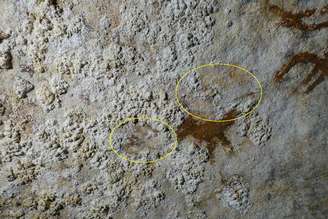 Contornos tênues de uma mão em uma superfície rochosa de calcário.