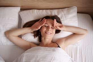 Happy girl waking up stretching arms on the bed in the morning