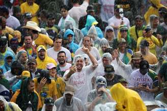 Apoiadores de Bolsonaro acenam sob chuva durante manifestação