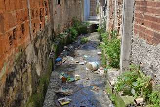 Canal de drenagem com aporte irregular de esgotamento sanitário e resíduos sólidos: problema costuma surgir quando o esgotamento sanitário e a drenagem urbana são planejados, operados e geridos como sistemas independentes.