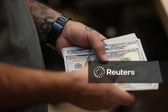 Homem conta notas de dólar
05/10/2025. Majid Asgaripour/WANA (West Asia News Agency) via REUTERS  
