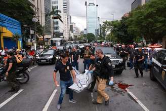 Policiais carregam corpo de suspeito morto; tiroteio interditou cruzamento das avenidas Faria Lima e Cidade Jardim.